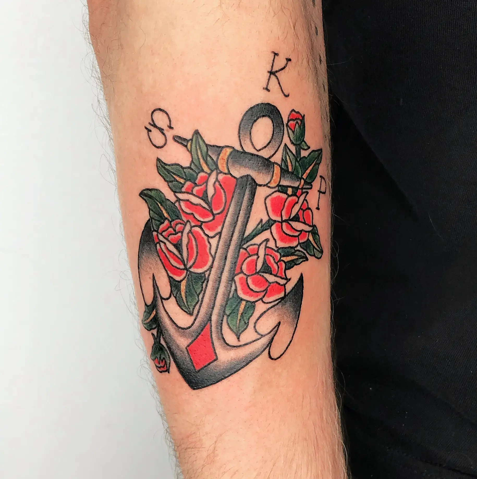 colored old school anchor tattoo with roses and initials on forearm