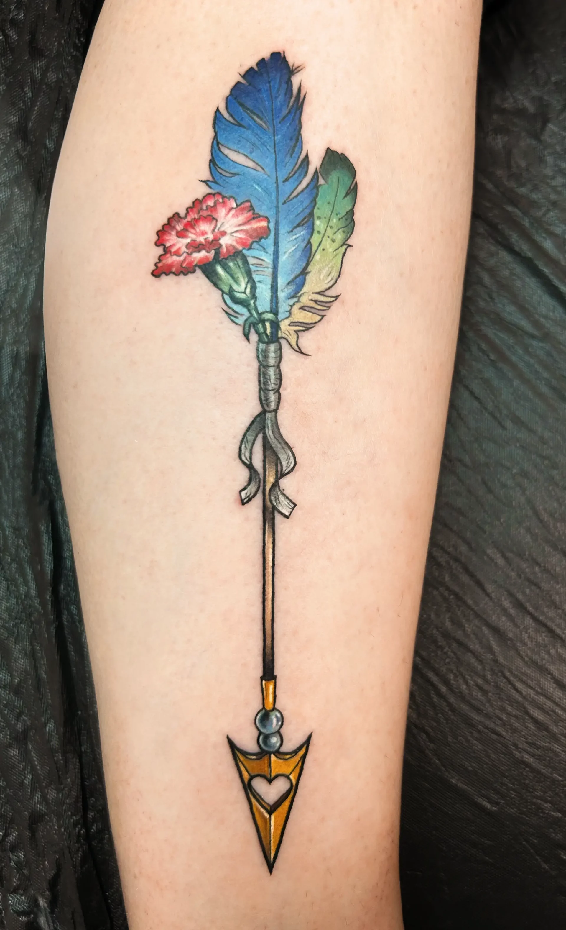 Colored arrow tattoo with feathers and flower