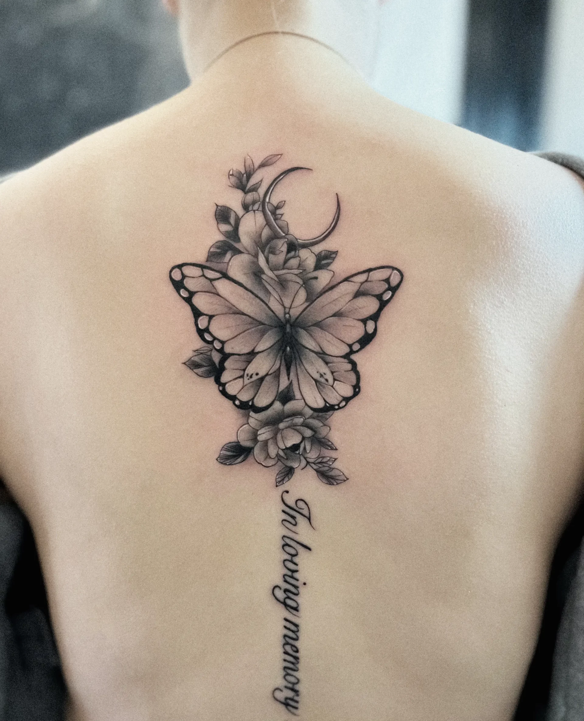 A woman's back with a black butterfly memory tattoo