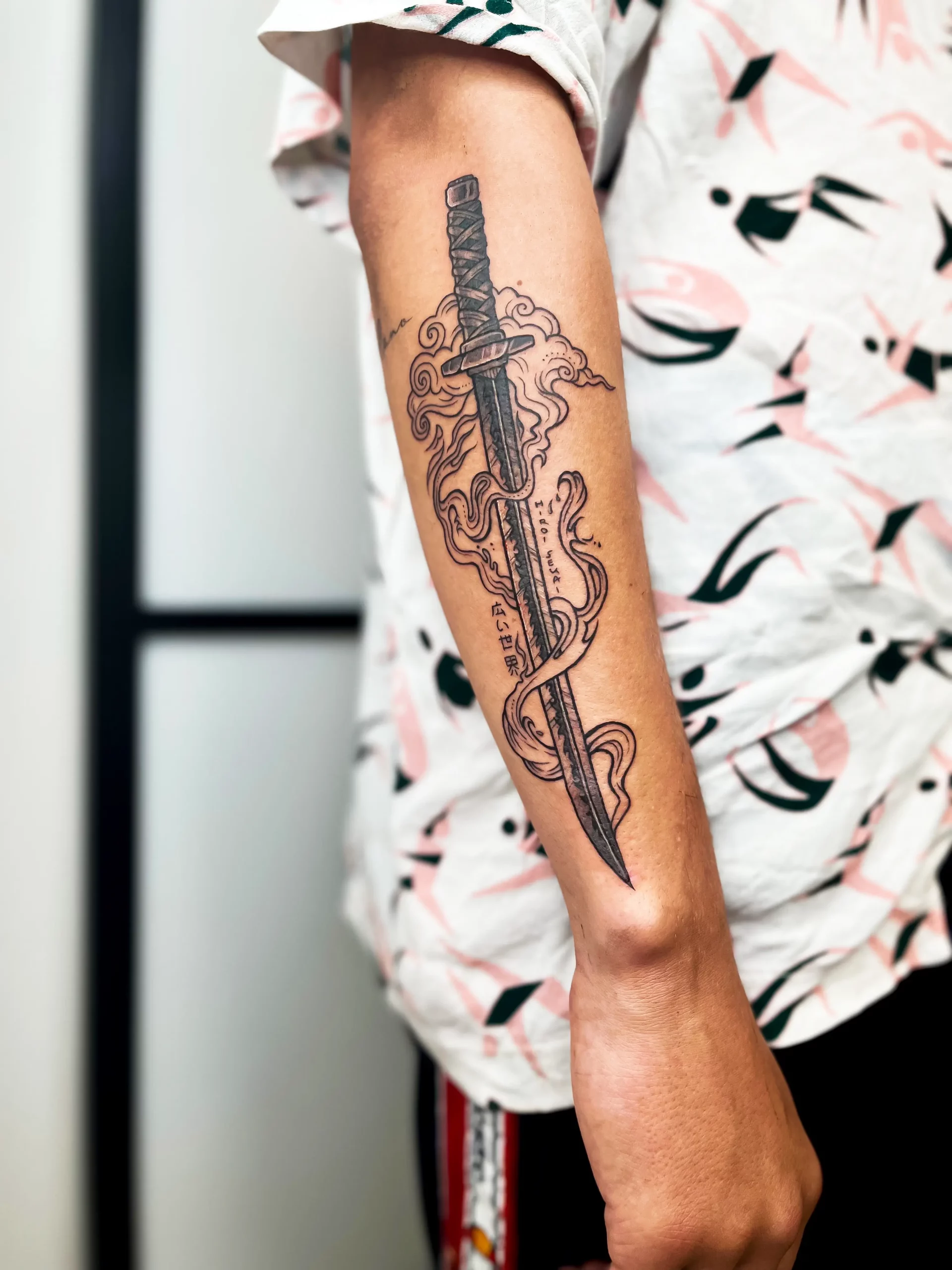 black sword tattoo on forearm