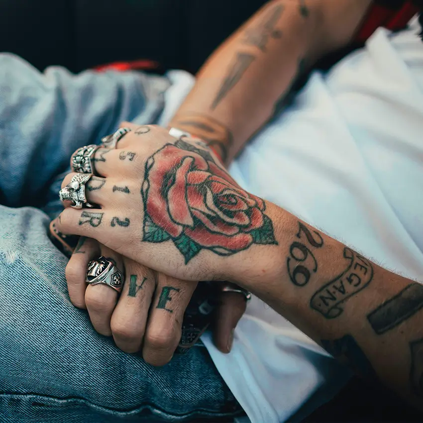 crossed male hands with silver rings and colorful tattoos